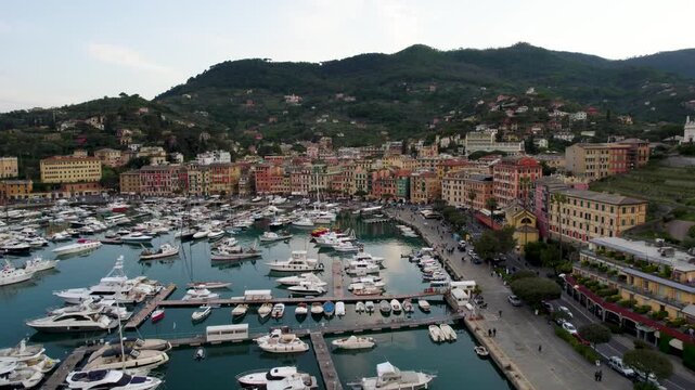 Aerial view of Santa Margherita Ligure harbor with luxury yachts and colorful mediterranean buildings at sunset.