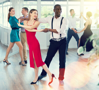Dance studio - a group of beautifully dressed people learn to dance tango