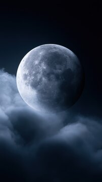 Full moon glowing brightly in the dark night sky surrounded by soft, wispy clouds creating a mysterious and serene atmosphere