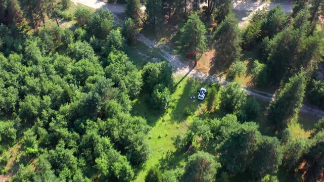Forest clearing appears in elevated aerial view beside a narrow mountain road near Mazeri, Svaneti, supporting campsite access, route planning, land use surveys and outdoor tourism development media.