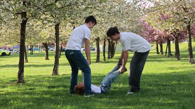 Happy children, teenage boys, playing jumping game in the park, springtime