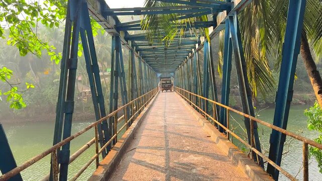Going through Sadolxem bridge surrounded by tropical greenery at golden sunset in South Goa, India