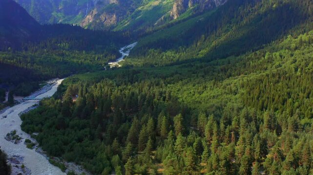 Dolra River winds in ascending aerial view through a forested mountain corridor near Mazeri, Svaneti, supporting watershed geography, trekking tourism, alpine research and Georgian travel campaigns.