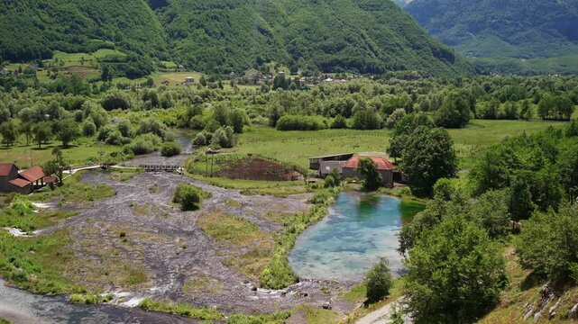 Panoramic aerial view of a scenic mountain valley where rivers and lakes meet, surrounded by majestic mountains and pristine wilderness.