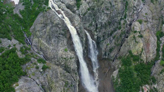 Shdugra Waterfall plunges, aerial view through fractured mountain rock below Ushba glaciers near Mazeri, Svaneti, supporting adventure tourism, meltwater research, geology education6 destination media