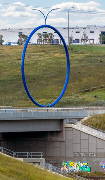 Calgary, Alberta, Canada. August 24, 2026. Eye-level view of the Travelling Light blue ring public art sculpture on a bridge overpass.