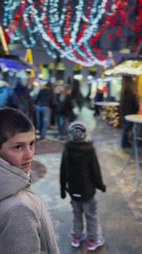 Two boys walking through illuminated Christmas market at night