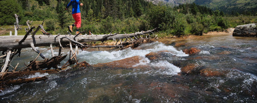 Woman walking on a one plank bridge in high altitude mountains