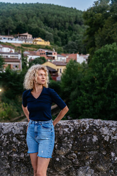 Portrait of Thoughtful Blonde Mature Woman by Stone Wall in Spanish Mountain Town