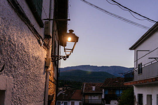 Glowing Vintage Street Lamp Over Traditional Spanish Village with Mountains at Blue Hour