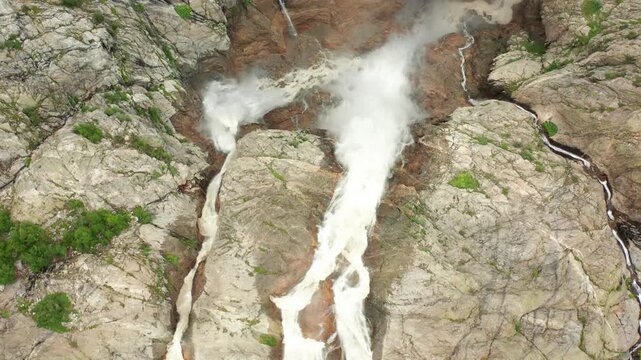 Shdugra Waterfall crashes in aerial view across fractured cliffs below Ushba glaciers near Mazeri, Svaneti, supporting hazard mapping, glacial hydrology, geological surveys and mountain tourism media.