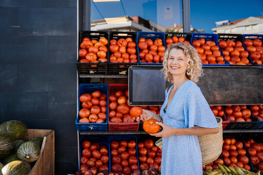 Cheerful Adult Woman in Her Forties Holding Fresh Tomatoes at Local Spanish Produce Market