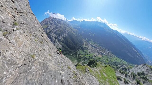 Climber traversing steep rocky ledge on Dauberhorn via ferrata near Leukerbad Switzerland