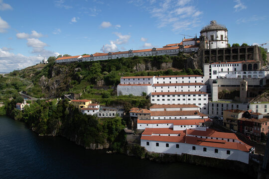 White houses with orange roof tiles next to the famous Ponte Dom Lu&iacute;s I bridge in Porto.