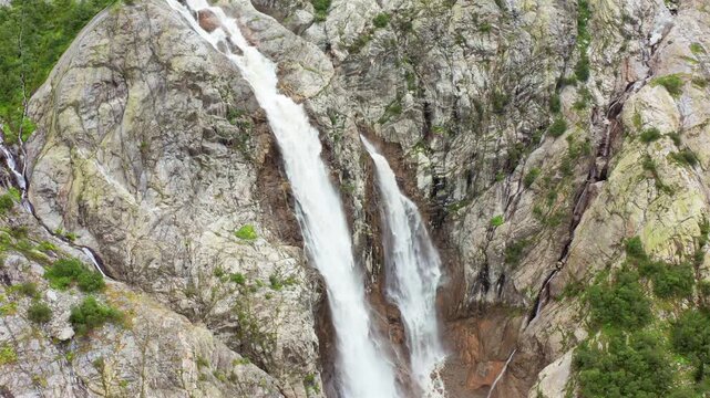 Shdugra Waterfall cascades in aerial view between rugged rock faces below Mount Ushba near Mazeri, Svaneti, supporting ecotourism, glacial hydrology, landscape research, Georgian destination promotion
