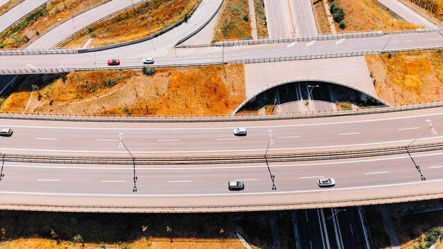 Roads intersecting in a highway system during daylight. Cars travel on various routes in an intricate highway layout in an urban area.