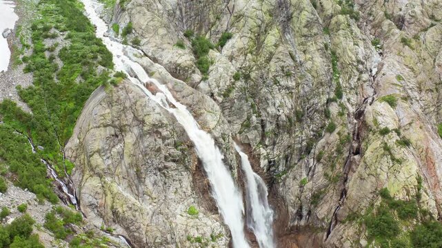 Shdugra Waterfall cascades in forward aerial view across fractured rock below Mount Ushba near Mazeri, Svaneti, supporting trekking tourism, glacial hydrology, erosion study and Georgian travel media.