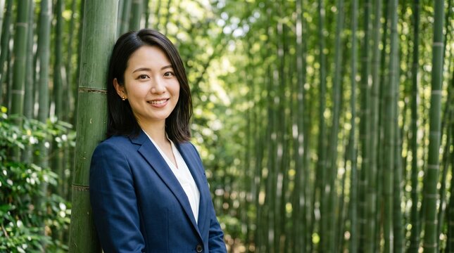 プロフィール写真をイメージした、豊かな竹林にある一本の竹にもたれかかり、穏やかな笑顔をカメラに向けている、知的な印象の20代日本人女性社員のバストアップポートレート