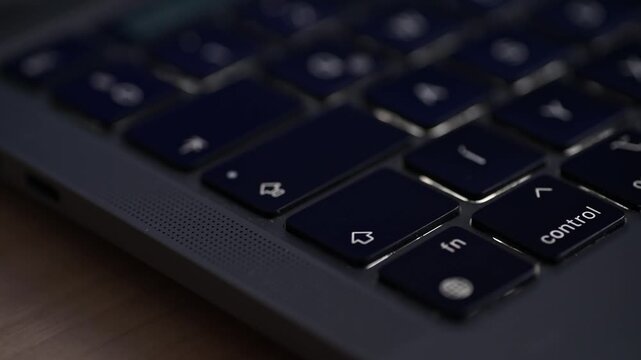 Close up of finger pressing illuminated laptop keyboard keys Fn and Control.