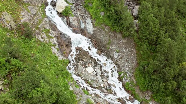 Shdugra stream descends in landing aerial view across a boulder field near Mazeri, Svaneti, supporting runoff research, watershed mapping, hiking tourism and Georgian alpine environment media.