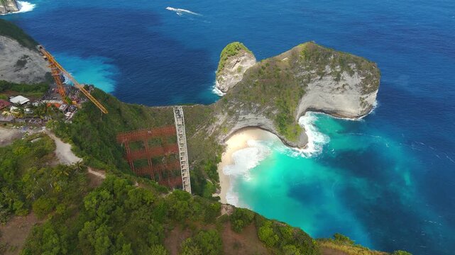Aerial panning view, glass elevator project subject to demolition order overlooking the iconic T-Rex cliff at Kelingking Beach, Nusa Penida, Indonesia