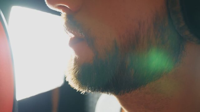 Mouth of male singer singing in sound studio. Unrecognizable man recording new song. Guy with beard sings to microphone. Working of creative musician. Show business concept. Slow motion Close up