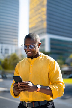 Near glass office building, African american smiling businessman using smartphone phone, texting, closeup portrait. Mature Black business man works as Freelancer, browsing shopping app, modern living.
