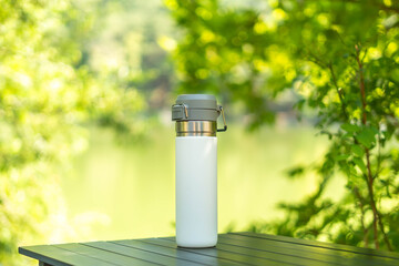 White water bottle thermos on wooden table outdoors