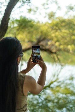 Woman capturing nature with smartphone at lake