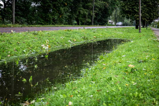 Long Roadside Puddle Flooding a Grassy Verge After Heavy Rain
