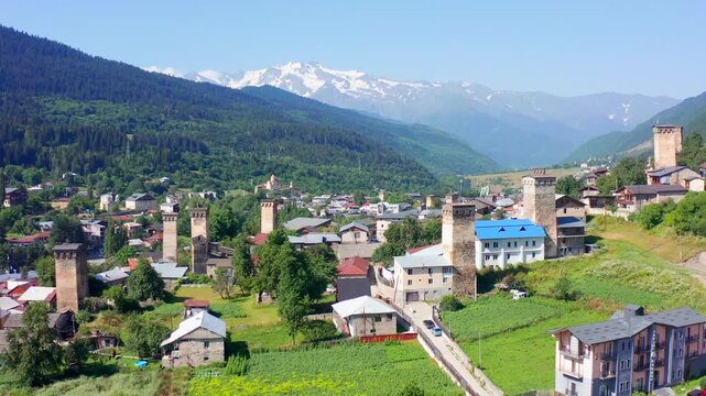 Mestia valley fills elevated aerial view as drone retreats from historic Svan towers, Caucasus ridges, supporting heritage tourism, mountain geography, regional travel, Georgian destination marketing