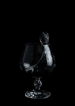 Water splashes inside a clear glass on a black background during a quiet moment