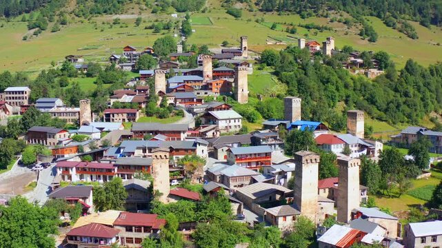 Svan tower district fills aerial view as the drone circles central Mestia homes and hillside fields, supporting medieval heritage, cultural tourism, settlement mapping, Georgian destination campaigns