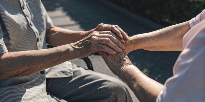 Compassion and care for the elderly with a caregiver holding the elderly person's hand