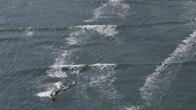 Aerial drone view of kite surfers riding the waves at My Hoa Beach in Vinh Hai, Khanh Hoa, Vietnam, showcasing a spectacular coastal landscape under bright sunlight.

