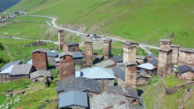 Chazhashi towers recede in backward aerial view above clustered stone homes and alpine roads in Upper Svaneti, supporting settlement mapping, heritage conservation, Georgian cultural geography media
