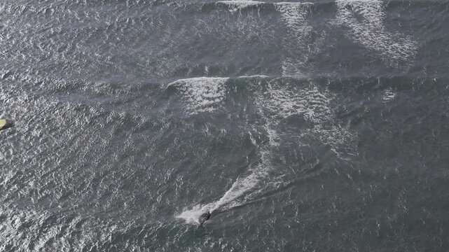 Aerial drone view of kite surfers riding the waves at My Hoa Beach in Vinh Hai, Khanh Hoa, Vietnam, showcasing a spectacular coastal landscape under bright sunlight.
