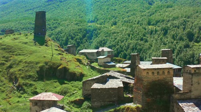 Medieval Svan towers pass in circling aerial view above dense stone houses in Ushguli, supporting defensive architecture research, cultural preservation, history education and Georgian tourism media.