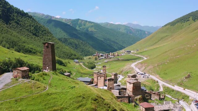Drone advances toward Ushguli village aerial view above medieval Svan towers, alpine roads in Upper Svaneti, Georgia, supporting heritage tourism, settlement geography, mountain destination promotion