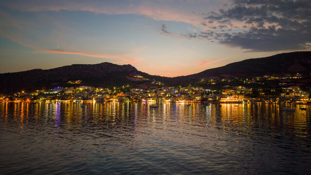 Aerial view of coastal town with lights reflection on calm sea water