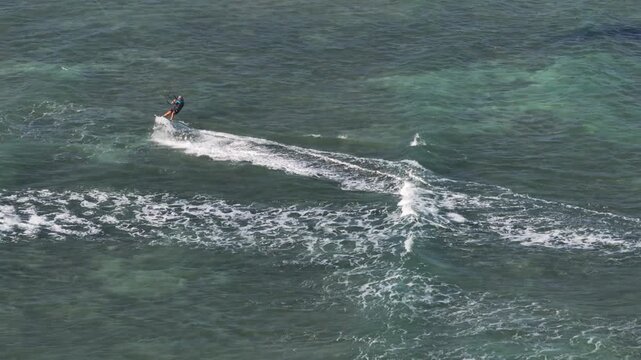 Aerial drone view of kite surfers riding the waves at My Hoa Beach in Vinh Hai, Khanh Hoa, Vietnam, showcasing a spectacular coastal landscape under bright sunlight.
