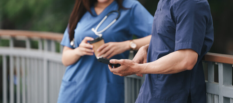 Cropped view of medical workers with smartphone and coffee during break