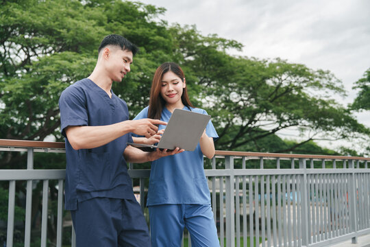 Asian healthcare workers smiling while looking at laptop during break