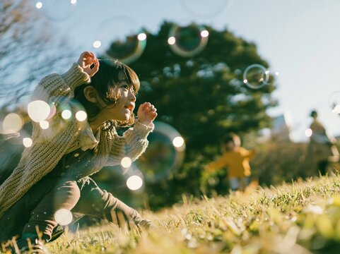 草原で無邪気にシャボン玉を追いかけて遊ぶ小さな女の子