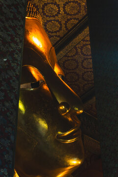 Close-Up Face of Giant Golden Reclining Buddha Framed by Ornate Columns at Wat Pho Temple in Bangkok Thailand