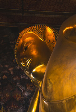 Serene Golden Face of Reclining Buddha Statue with Temple Mural at Wat Pho in Bangkok Thailand