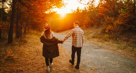 A man and woman embrace and kiss each other on a path in an autumn forest. A loving couple enjoys...