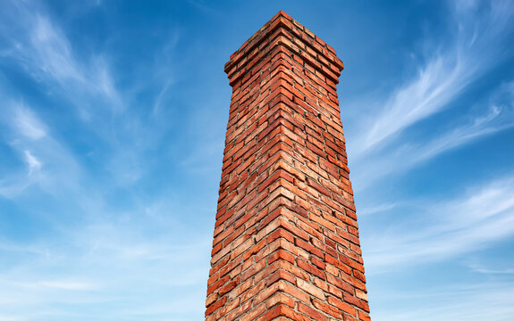 Red brick chimney top against blue cloudy sky