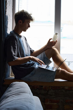 Recovering man checks medicine while shopping online from home with laptop. Concept of healthcare accessibility, recovery support, remote ordering and home comfort.
