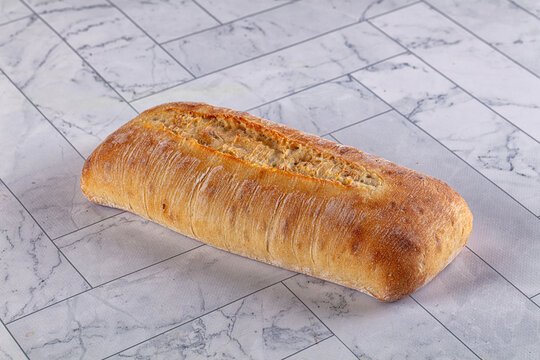 Freshly baked artisan bread loaf on marble tile surface